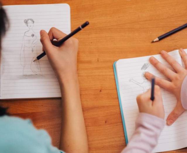 Two children drawing in notebooks