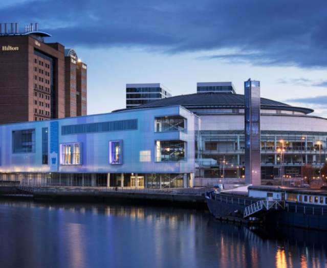 Photo of the waterfront hall in Belfast overlooking the water with the Hilton hotel in the background.