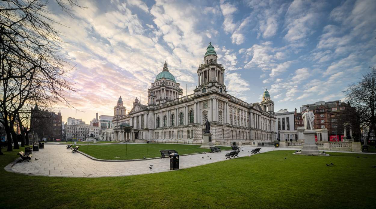 Photo of Belfast City Hall from outside looking at the grass areas and benches.