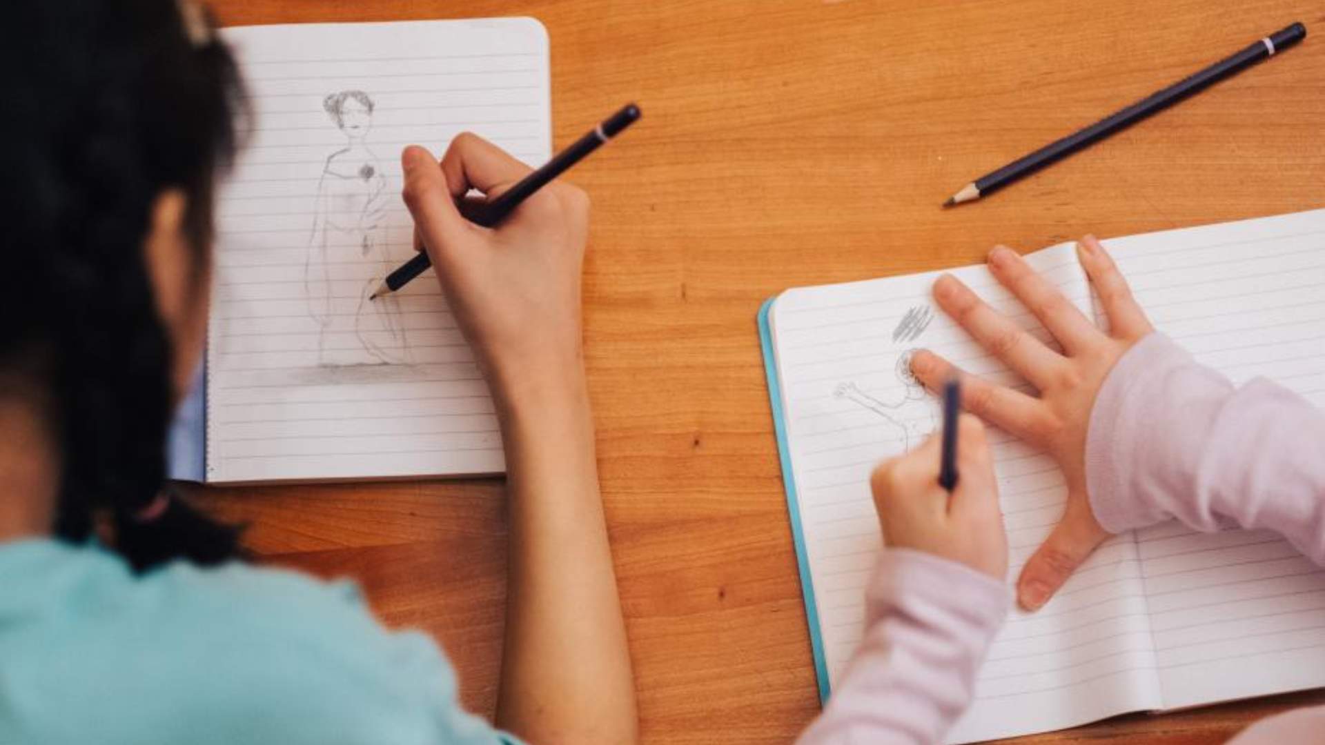 Two children drawing in notebooks
