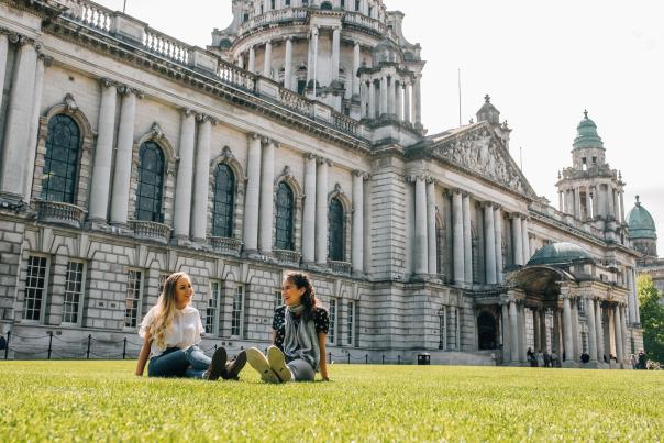 Two young women sitting on the front lawn at Belfast City Hall