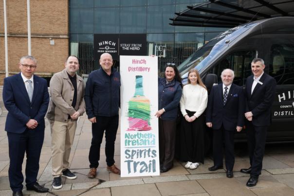 Adults standing outside beside a Hinch Distillery van and a “Northern Ireland Spirits Trail” sign.