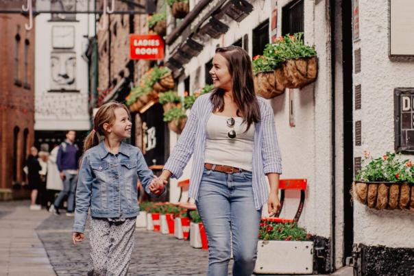 Mother and daughter holding hands walking through Commercial Court in Belfast