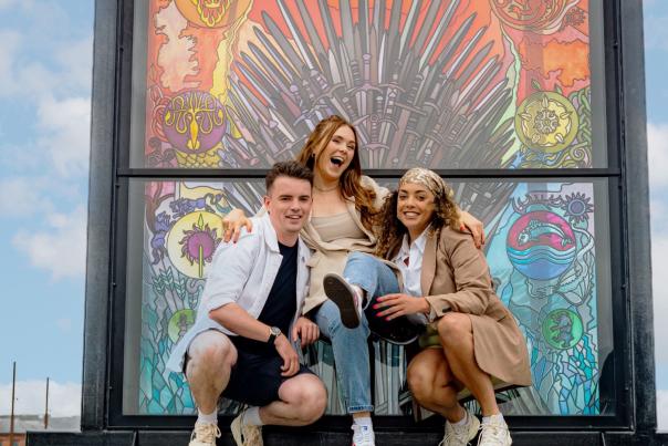 Group of three people posing for a phone at one of the stained glass windows on the Glass of Thrones Trail.