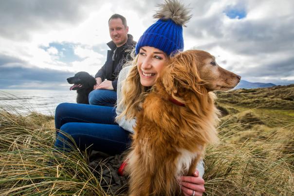 Man and Woman with two dogs on the beach at Murlough Bay