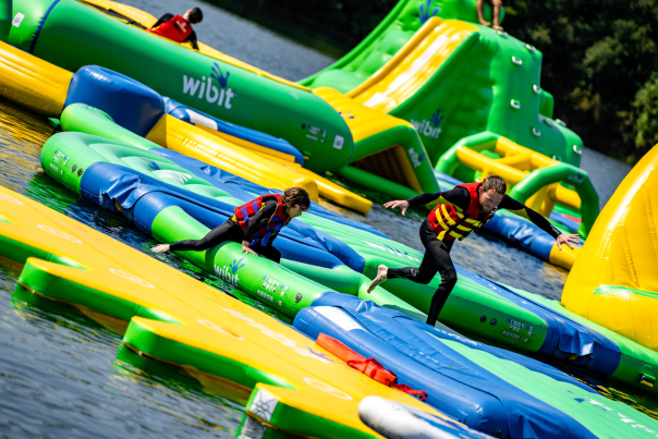 Two people running across inflatables on water