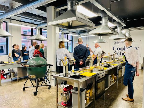 A group of people learning at the Cookery School at Waterman House.