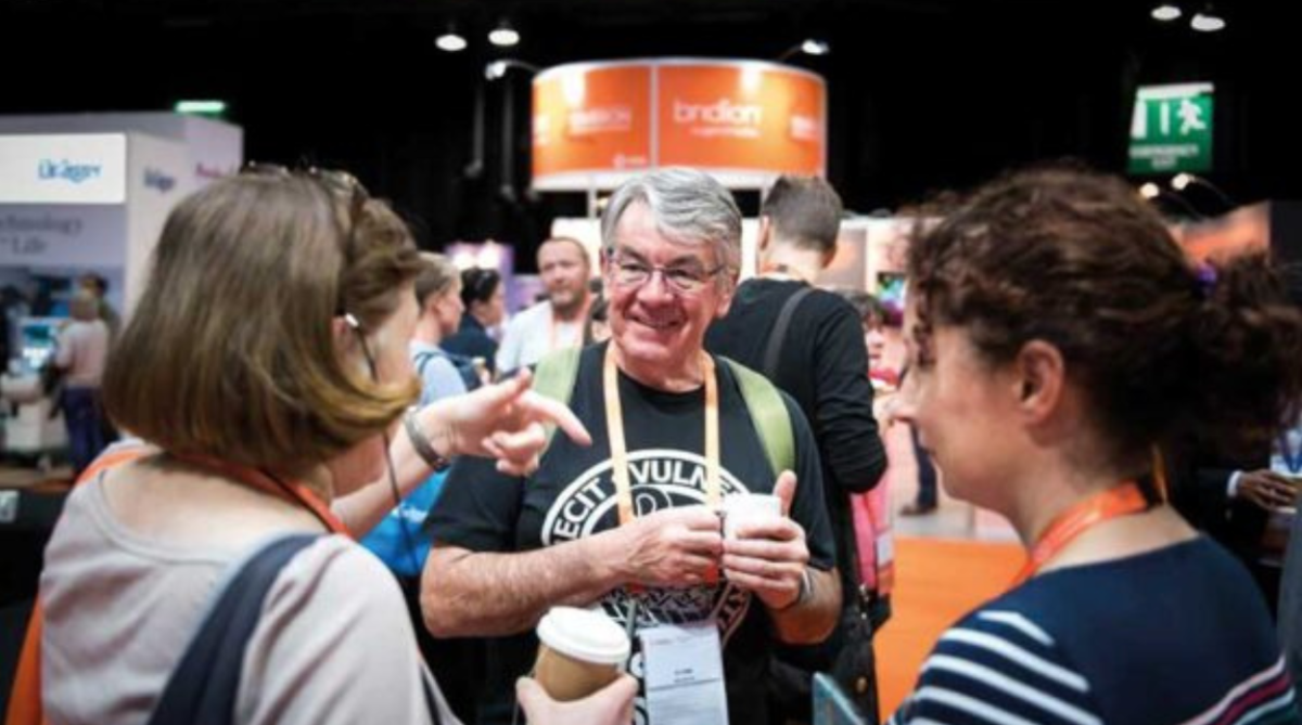3 people talking at a business conference in Belfast drinking coffee.
