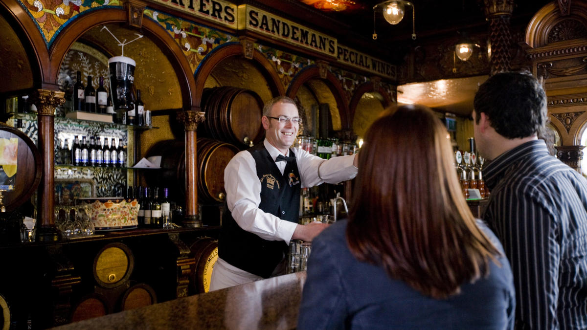 Barman in the Crown Liquor Saloon serving customers.