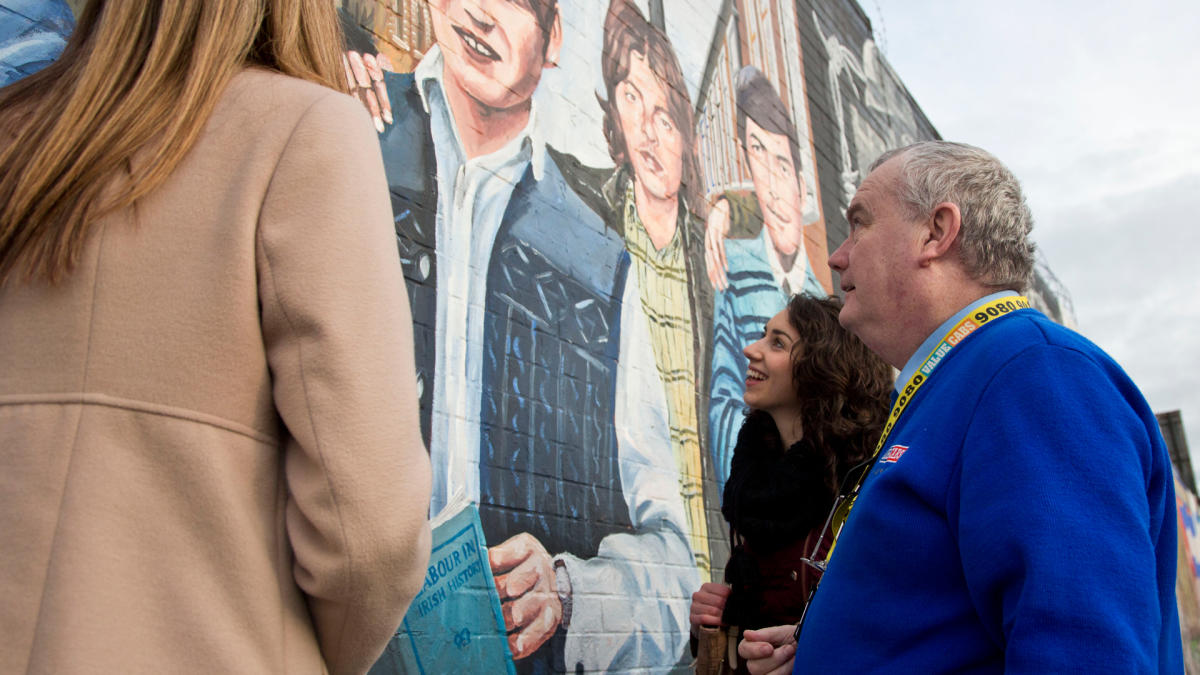 A group of girls looking at the peace walls during a value cabs taxi tour.