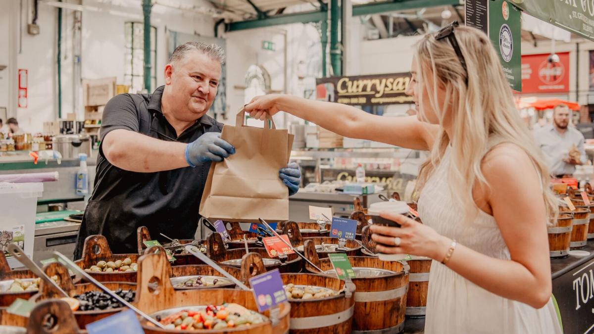 Woman buying some food goods from a seller at St George's Market