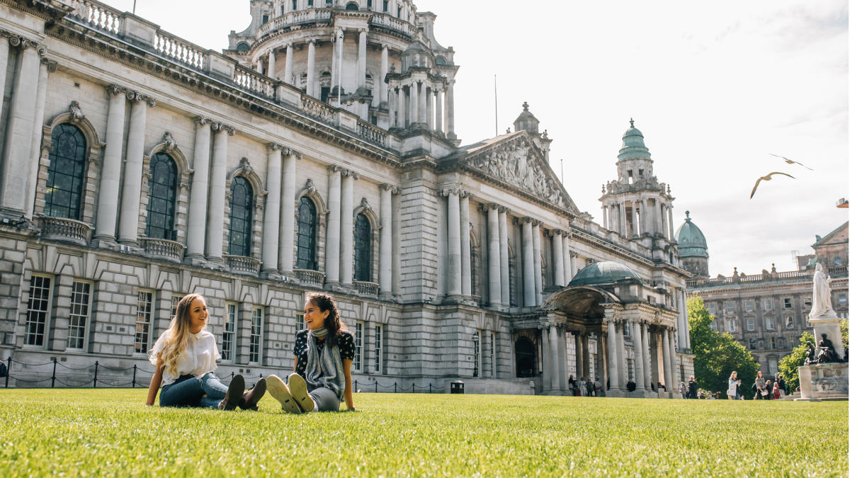 Two young women sitting on the front lawn at Belfast City Hall