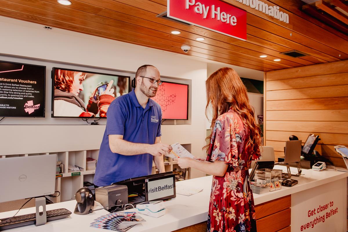 Man in Visit Belfast welcome centre helping tourists with information