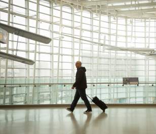 Man dressed in black alone walking through bright white airport