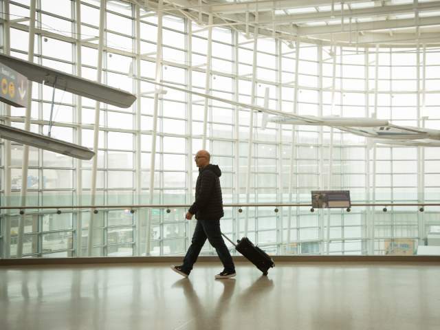 Man dressed in black alone walking through bright white airport