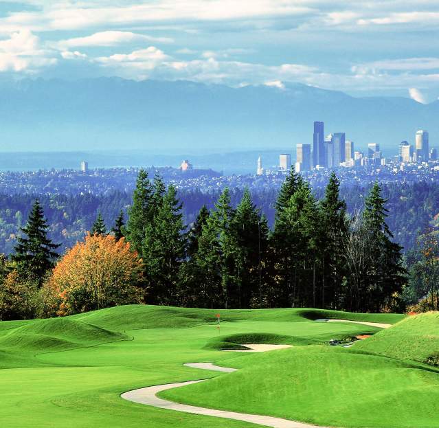 Scenic view of Bellevue Golf Course featuring manicured grass, trees, and the Seattle skyline on a sunny day