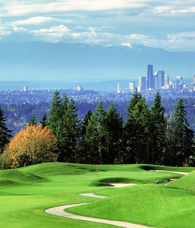 Scenic view of Bellevue Golf Course featuring manicured grass, trees, and the Seattle skyline on a sunny day