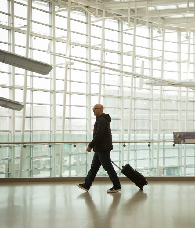 Man dressed in black alone walking through bright white airport