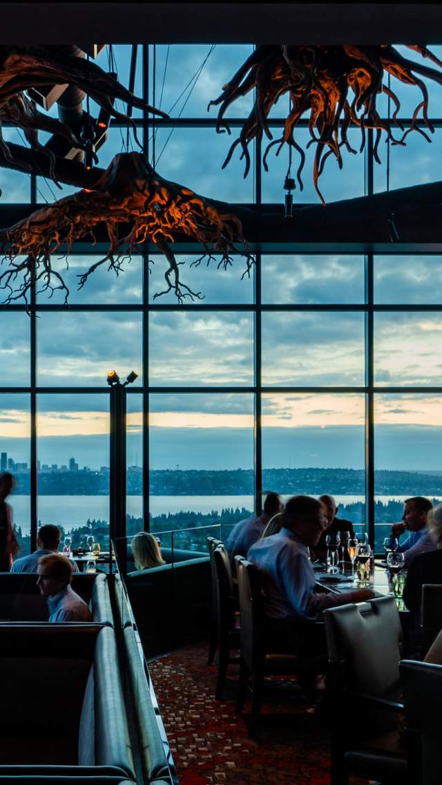 Beautiful chandlers inspired by tree roots set the scene of an expansive dining room of the rooftop restaurant overlooking Lake Washington and Seattle