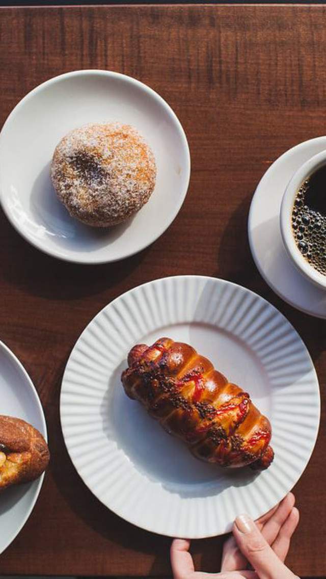 savory pastries on white plates and a cup of rich, black coffee on an oak table