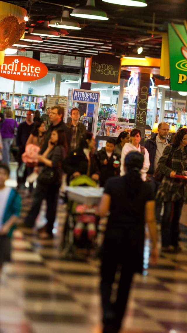 People walking through the Crossroads food court with various international food stalls in the background.