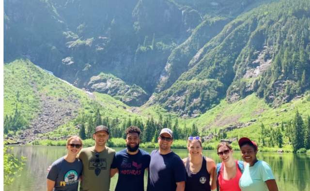 Hiking group posing in front of a lake hike