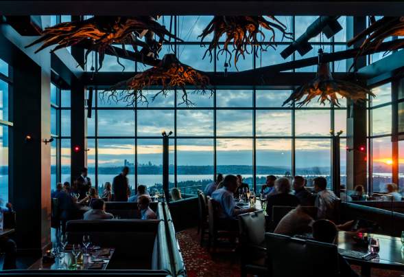 Beautiful chandlers inspired by tree roots set the scene of an expansive dining room of the rooftop restaurant overlooking Lake Washington and Seattle