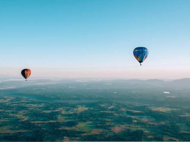 Passengers enjoy the scenic beauty of the Pacific Northwest from the basket of hot-air balloons.