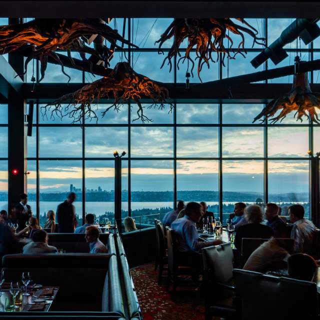 Beautiful chandlers inspired by tree roots set the scene of an expansive dining room of the rooftop restaurant overlooking Lake Washington and Seattle