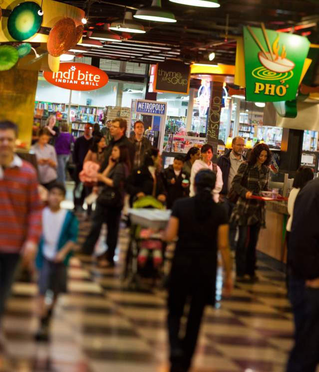 People walking through the Crossroads food court with various international food stalls in the background.