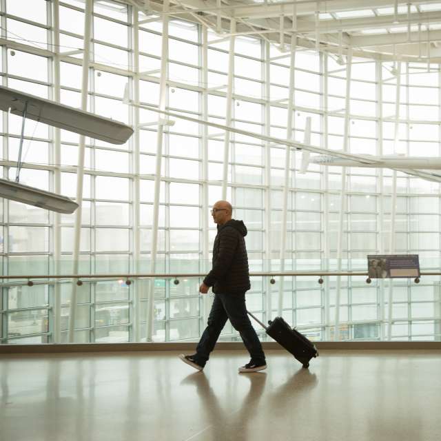 Man dressed in black alone walking through bright white airport