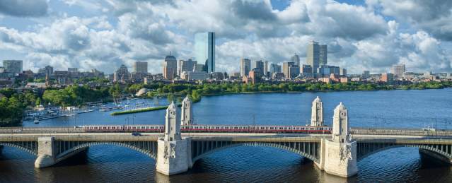 MBTA red line Train traveling over the Longfellow Bridge with the Boston skyline in the background.
