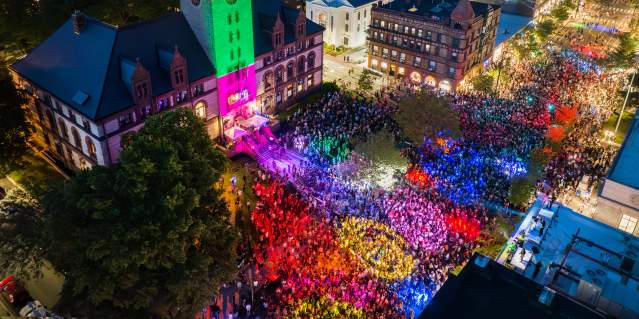 Aerial view at night of the Cambridge Dance Party, building and crowd illuminated by colorful lights