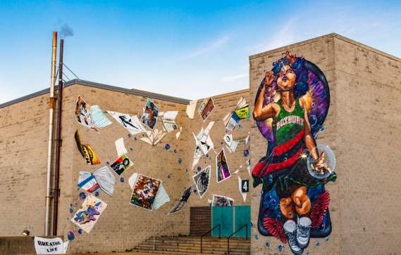 Mural depicting child wearing a dress reading Roxbury blowing bubbles and surrounded by blowing posters and books