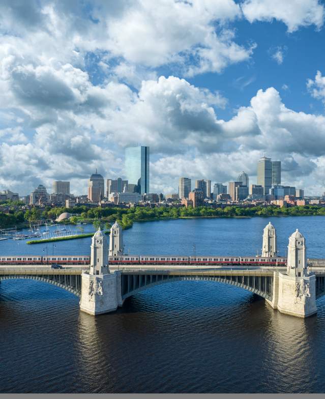 MBTA red line Train traveling over the Longfellow Bridge with the Boston skyline in the background.