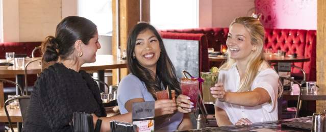 3 women smiling with cocktails