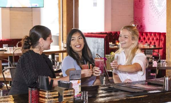 3 women smiling with cocktails