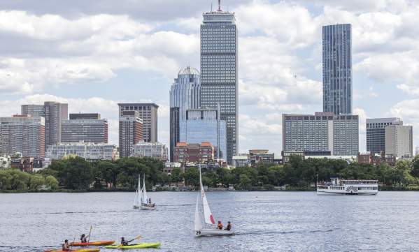 A few kayaks and sailboats on the Charles River with the Boston skyline in the background