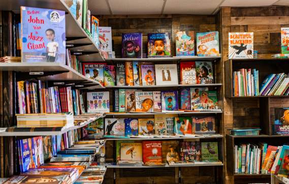 Two walls with floor to ceiling bookshelves filled with children's books at the Frugal Bookstore