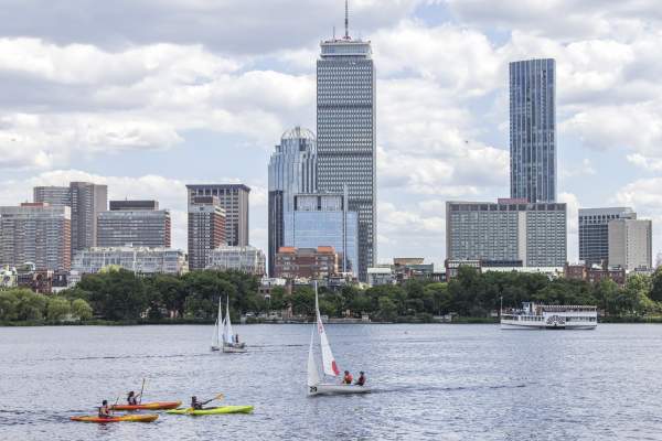 A few kayaks and sailboats on the Charles River with the Boston skyline in the background
