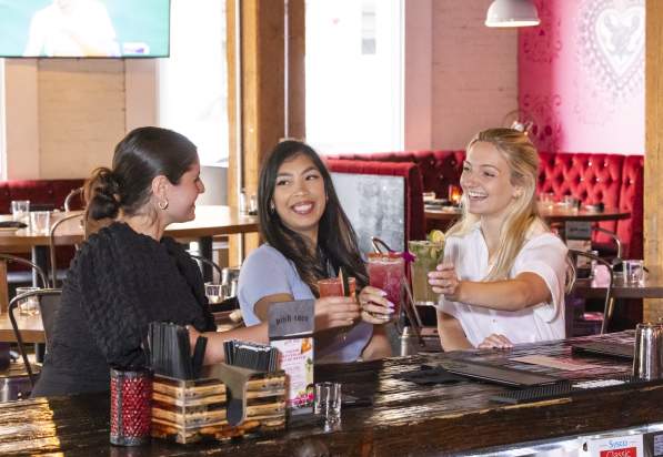 3 women smiling with cocktails