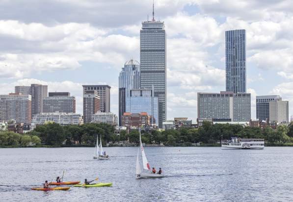 A few kayaks and sailboats on the Charles River with the Boston skyline in the background