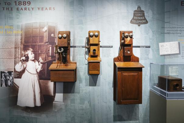 Antique photo of a girl holding an old wooden telephone