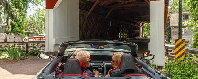a couple drives through a covered bridge