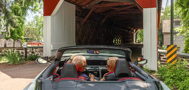 a couple drives through a covered bridge