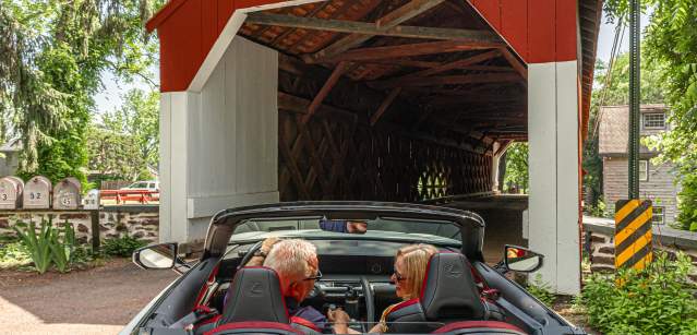 a couple drives through a covered bridge