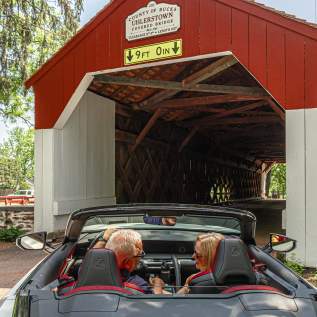 a couple drives through a covered bridge