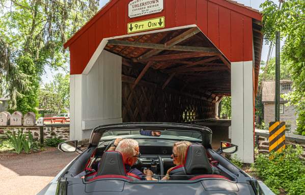 a couple drives through a covered bridge