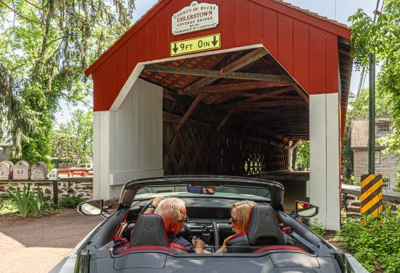 a couple drives through a covered bridge