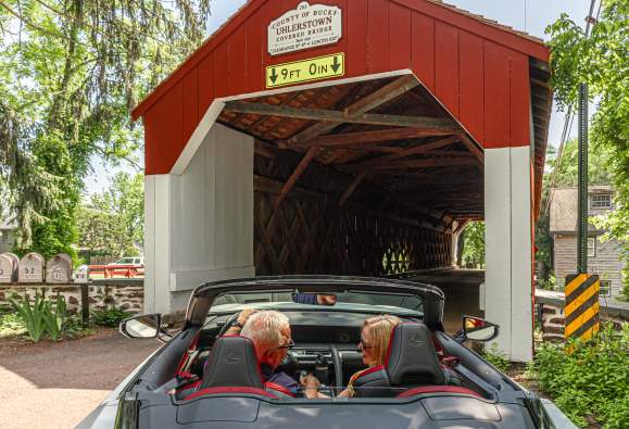 a couple drives through a covered bridge